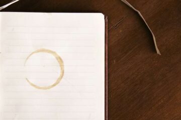 Comma before or after such as illustrated by an open lined notebook with a coffee ring on a dark desk