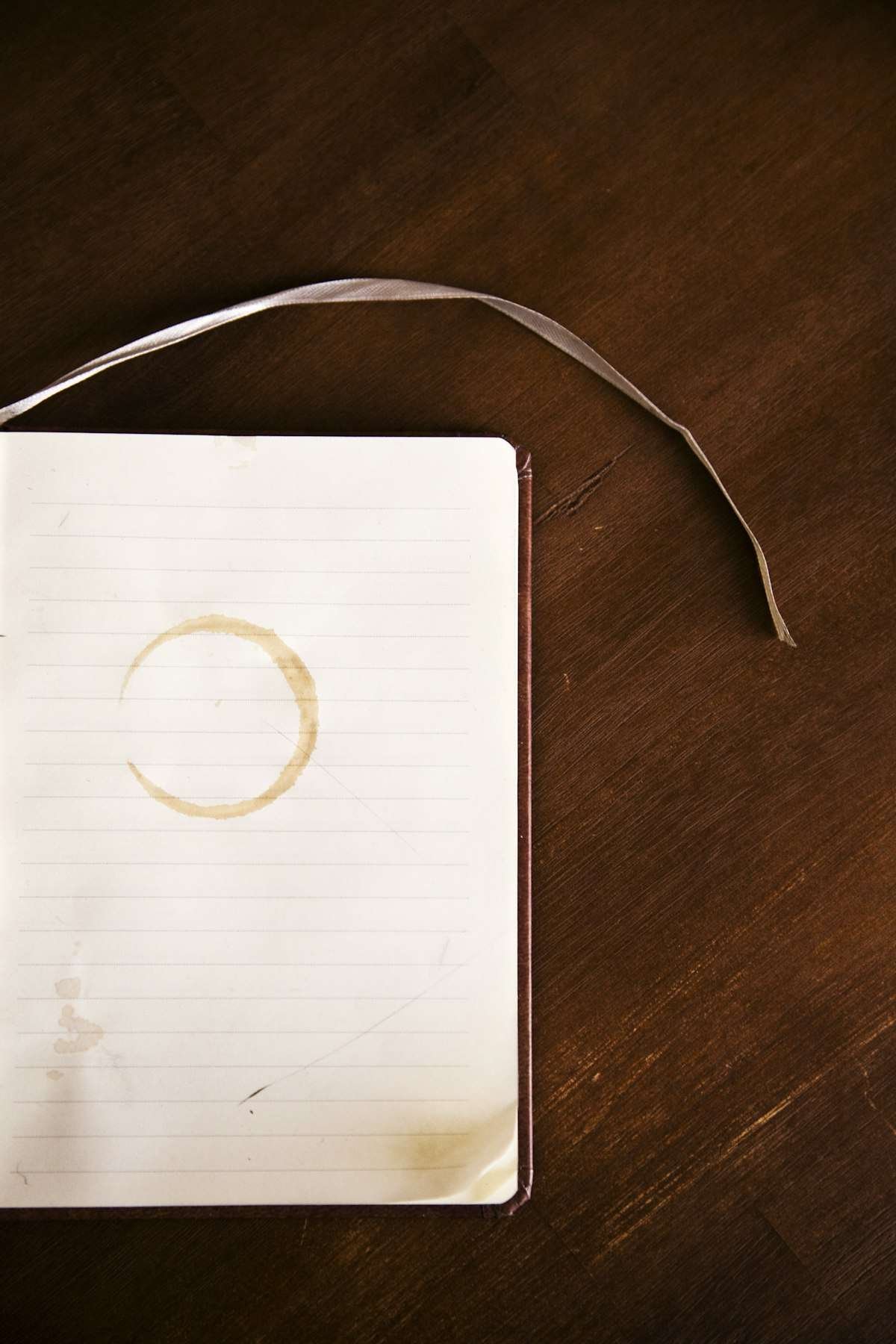 Comma before or after such as illustrated by an open lined notebook with a coffee ring on a dark desk