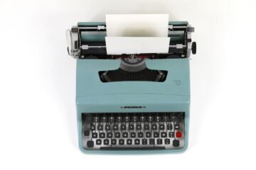 Comma before or after so shown by a vintage teal typewriter with a sheet of paper loaded
