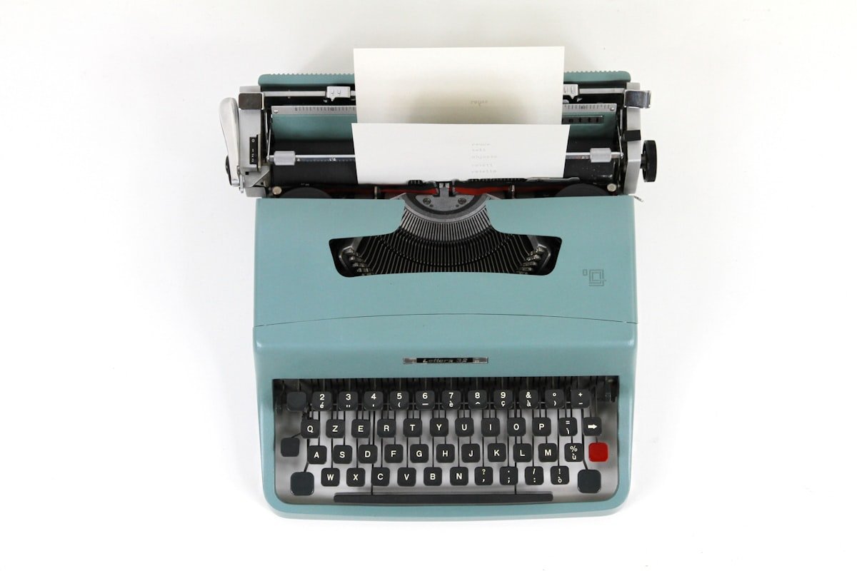 Comma before or after so shown by a vintage teal typewriter with a sheet of paper loaded