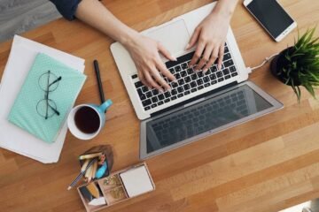 How to reply to email demonstrated by hands typing a response on a laptop at a tidy wooden desk