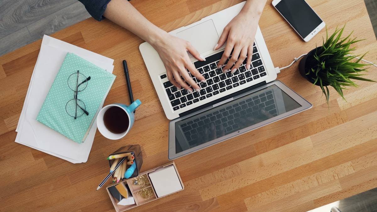 How to reply to email demonstrated by hands typing a response on a laptop at a tidy wooden desk