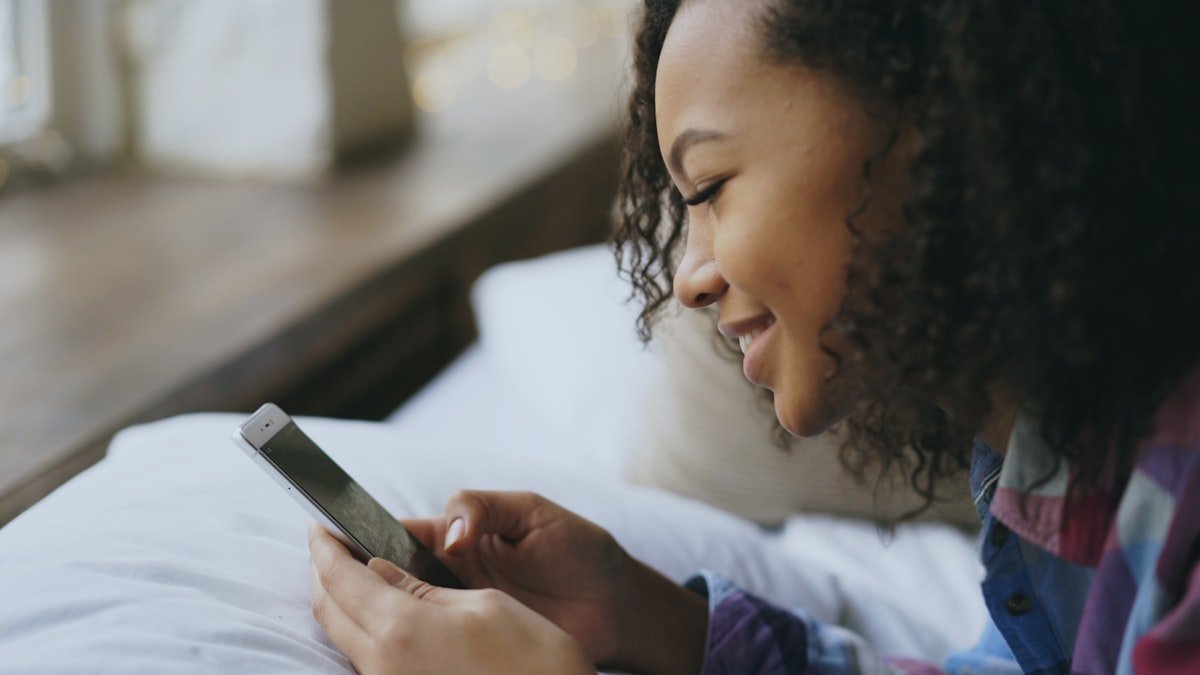 HYS meaning in text shown by a woman in bed smiling at a good-morning message on her phone