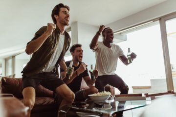 LFG meaning slang in action as three friends jump up cheering at a game on TV