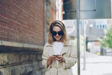 OMW meaning in text captured by a woman texting on my way while walking down a city street