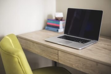 Out of office message examples represented by an empty desk with a closed laptop and vacant chair