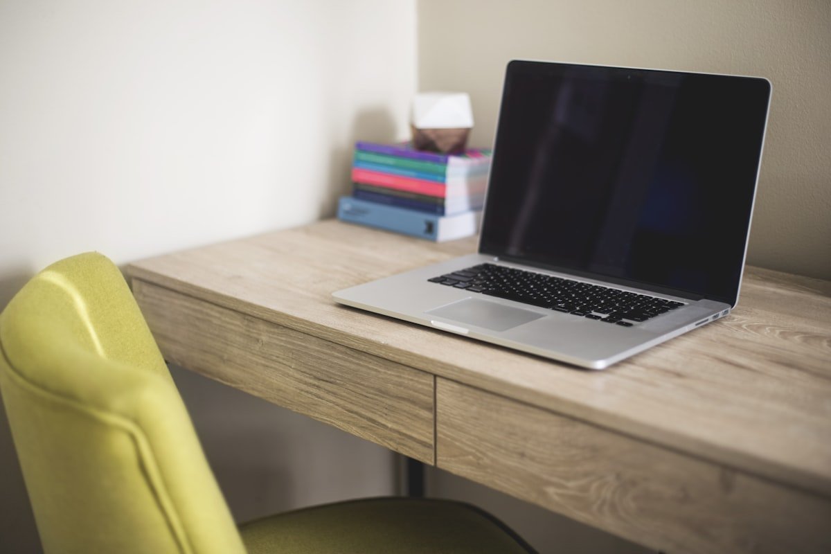 Out of office message examples represented by an empty desk with a closed laptop and vacant chair