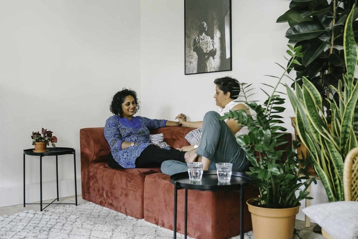 What to say when someone is dying from cancer shown by two friends sitting together on a sofa in quiet conversation